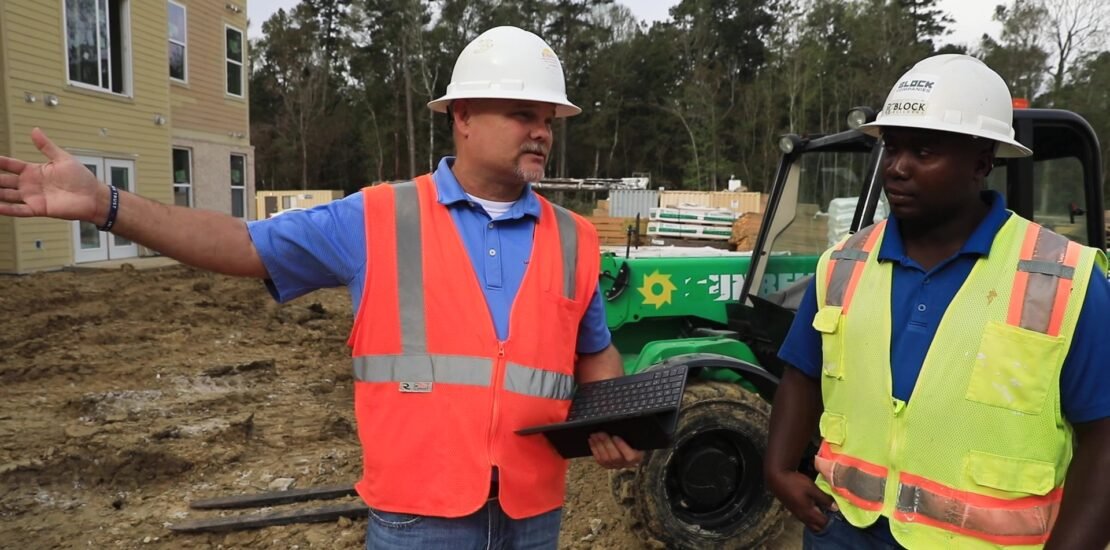 RiskWise safety consultant conducting a job site inspection, discussing safety protocols with a construction worker.