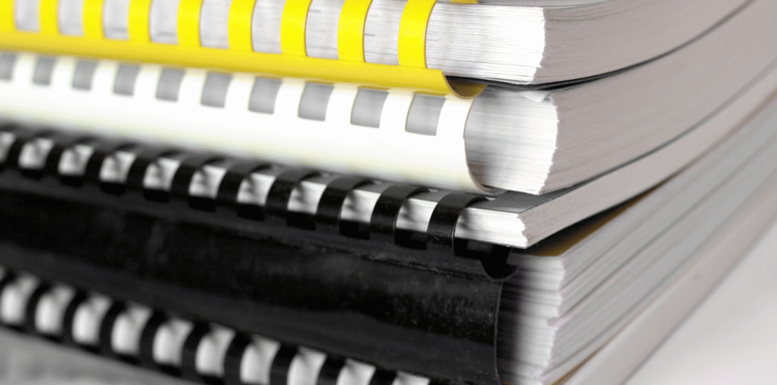 Stack of comb-bound safety manuals representing customized OSHA-compliant written safety programs by RiskWise